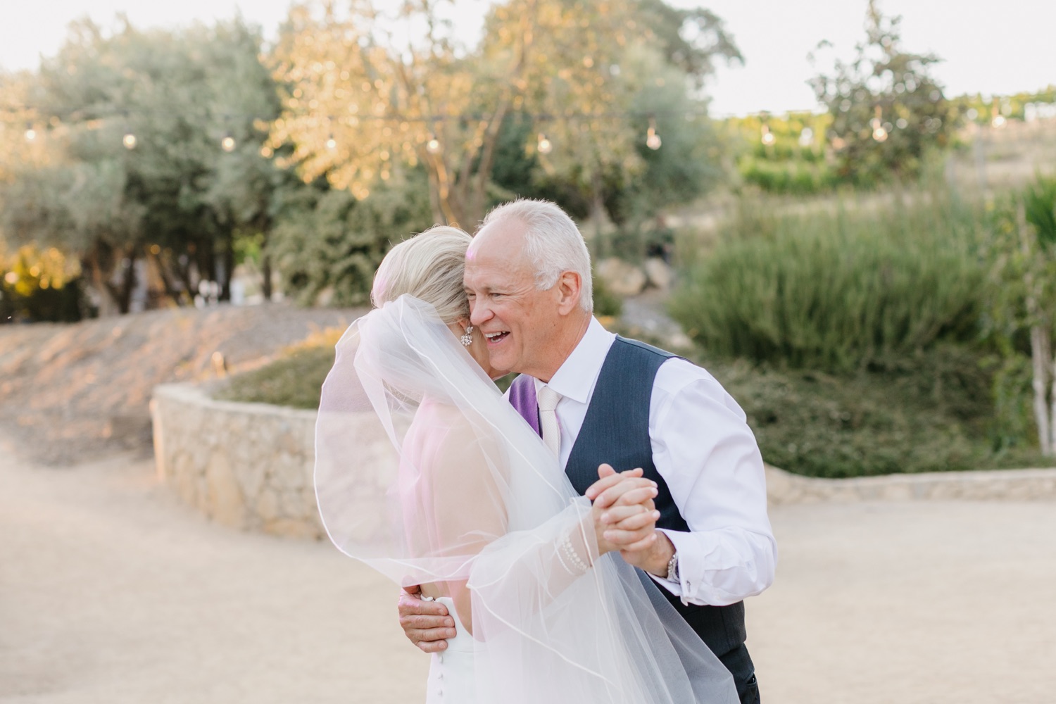 father of bride smiling while embracing his daughter during father daughter dance at her terra mia wedding