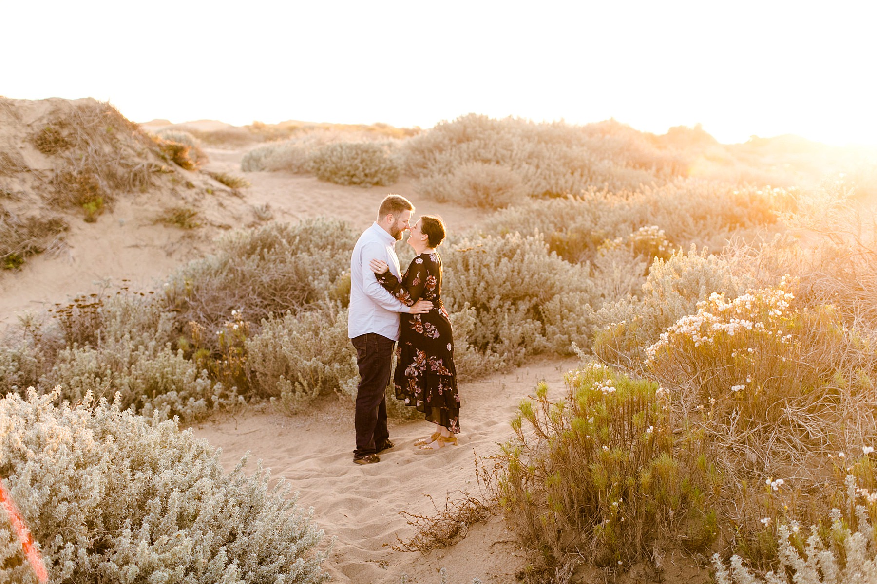 engaged couple embraces on the los osos sand dunes at sunset