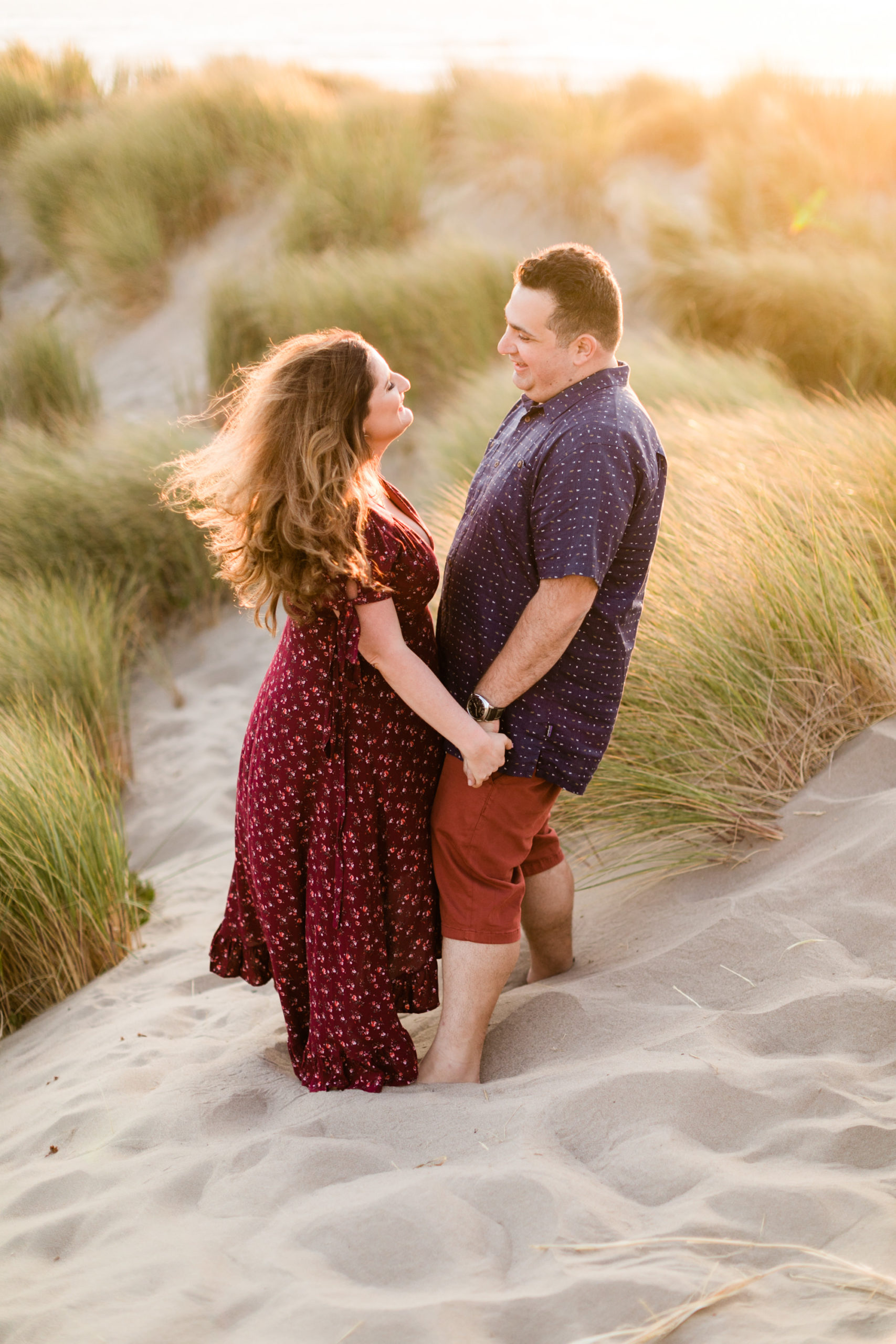 couple smiling at each other during engagement session at Morro Rock in Morro Bay ca