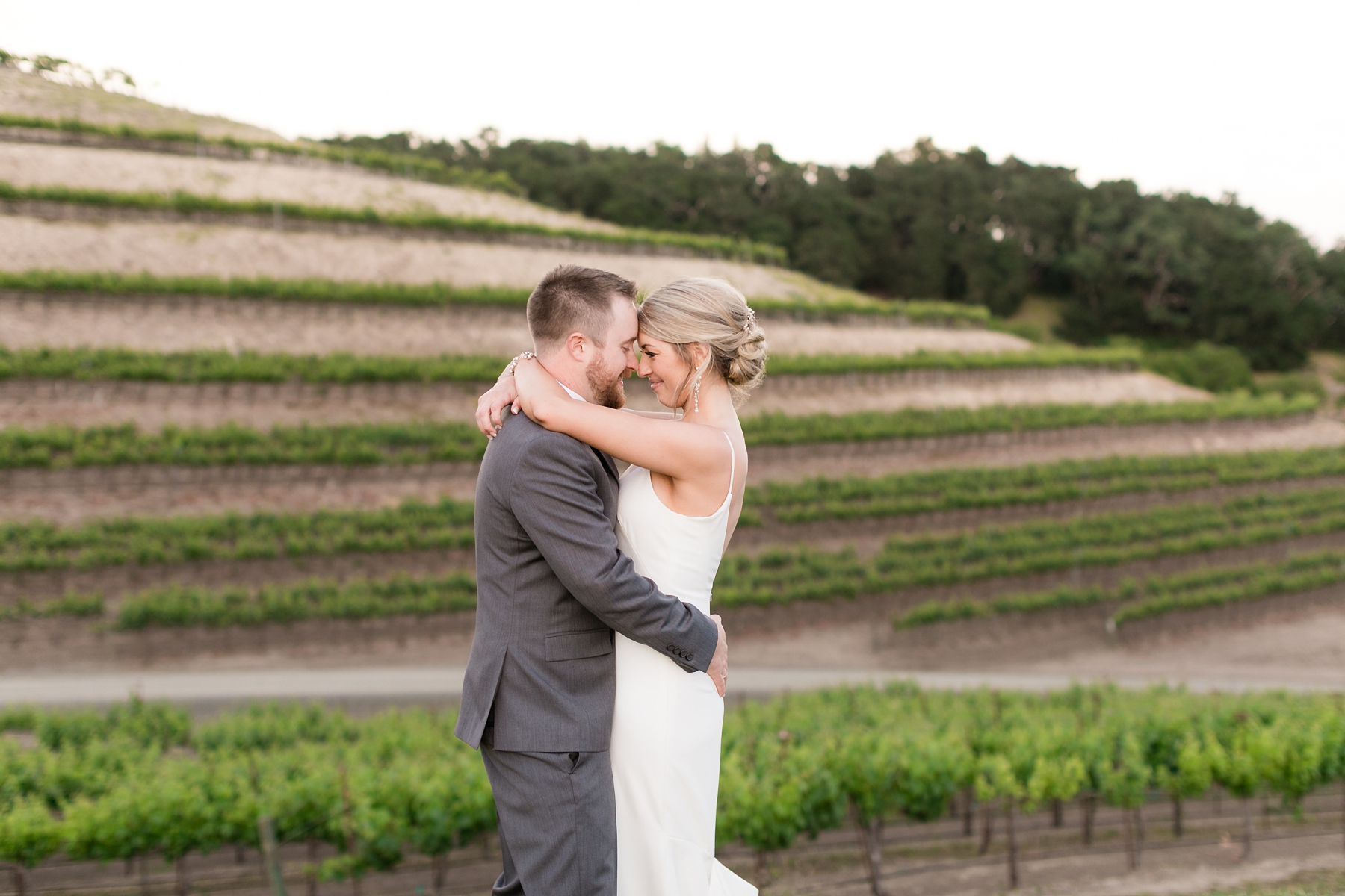 Bride and groom embrace and laugh in the vineyards at their foggy hilltop winery wedding in paso robles, california