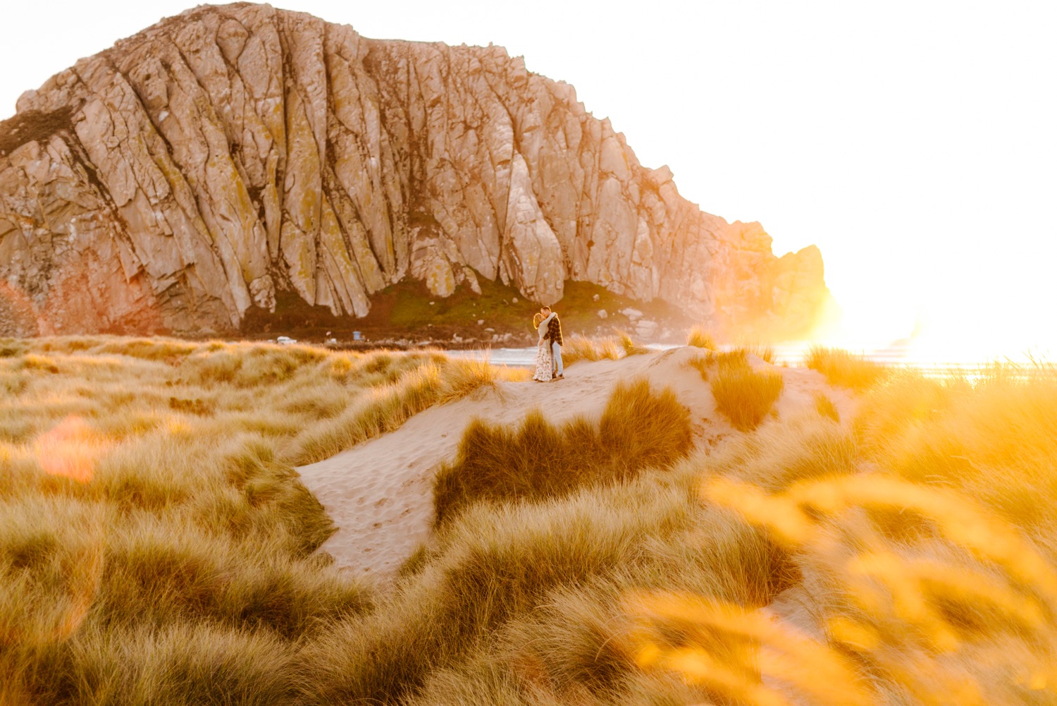 bride and groom in front of morro bay rock at engagement session