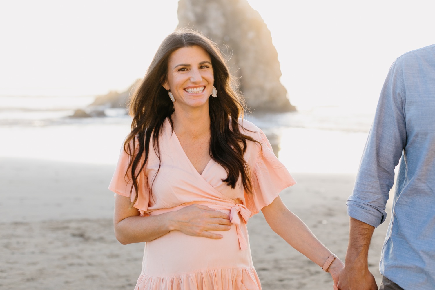 couple walking and smiling on the beach in Pismo, california at their maternity session with tayler enerle
