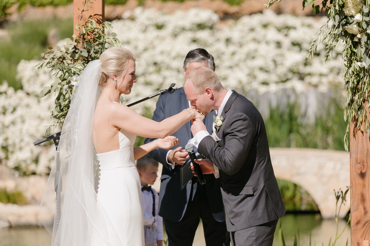 groom kissing brides hand at wedding ceremony