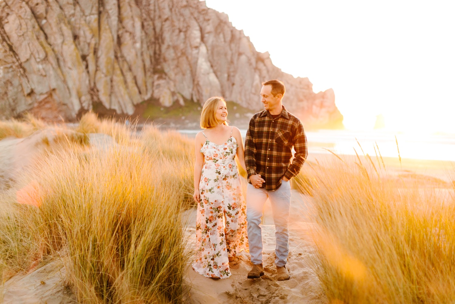 couple walking together at their engagement session at morro bay rock california by tayler enerle