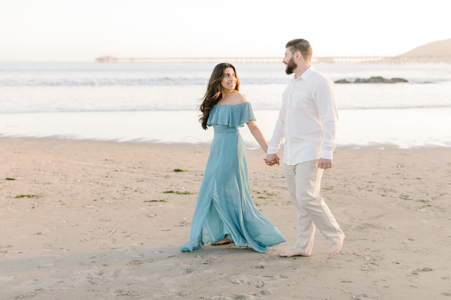 couples walking on the beach at their engagement session at Avila beach 