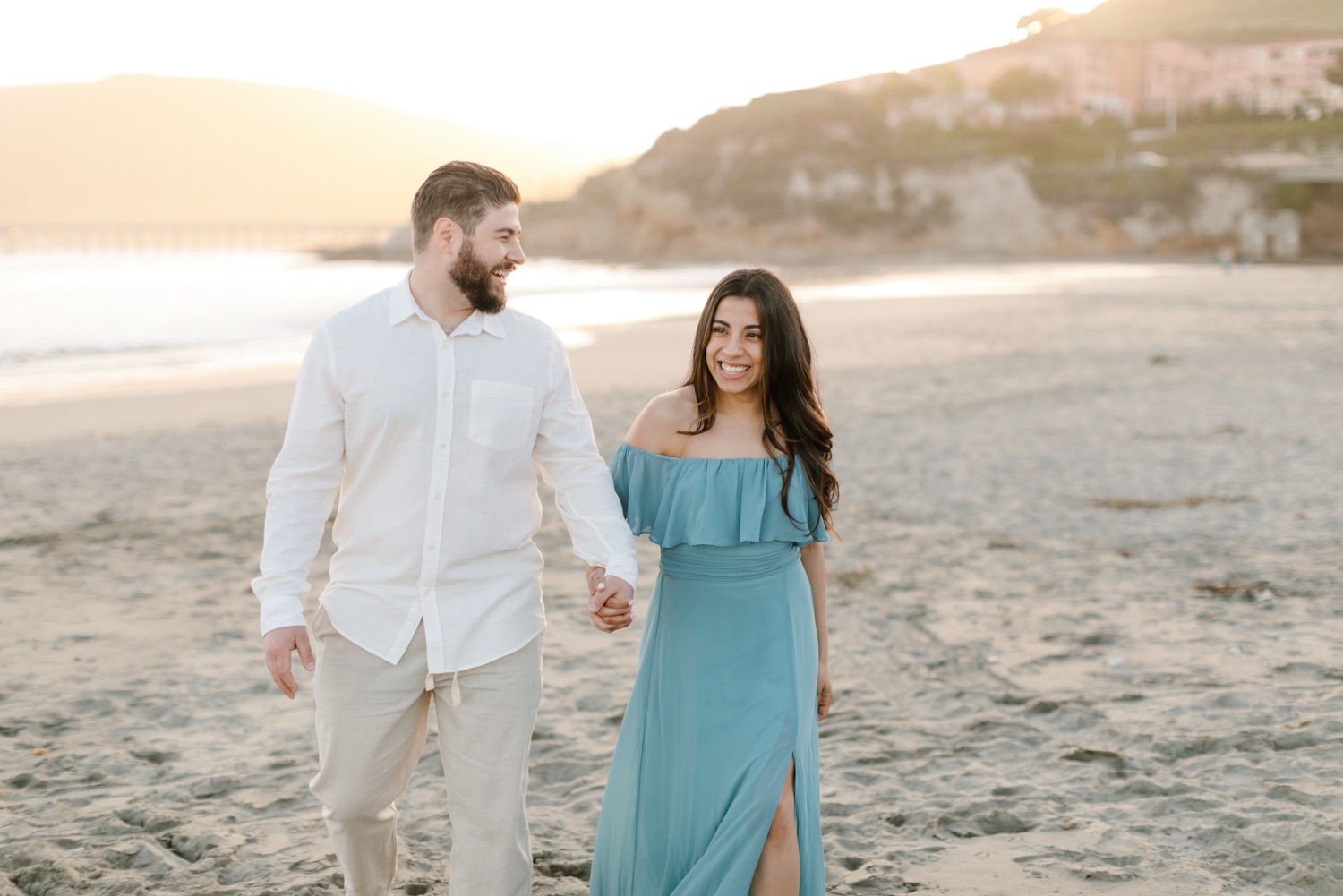 couple walking on the beach in avila at their engagement session
