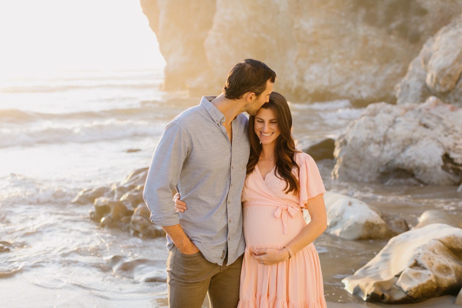 man kissing his pregnant wife at maternity session in Pismo Beach, california