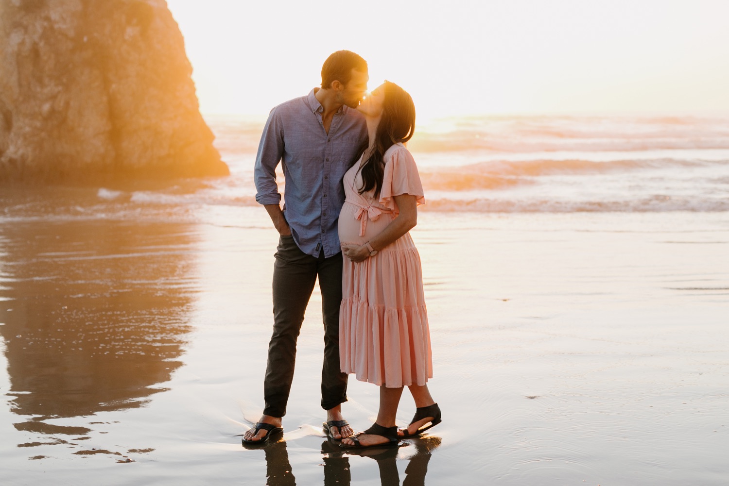 sun drenched maternity session where couple are kissing on the beach