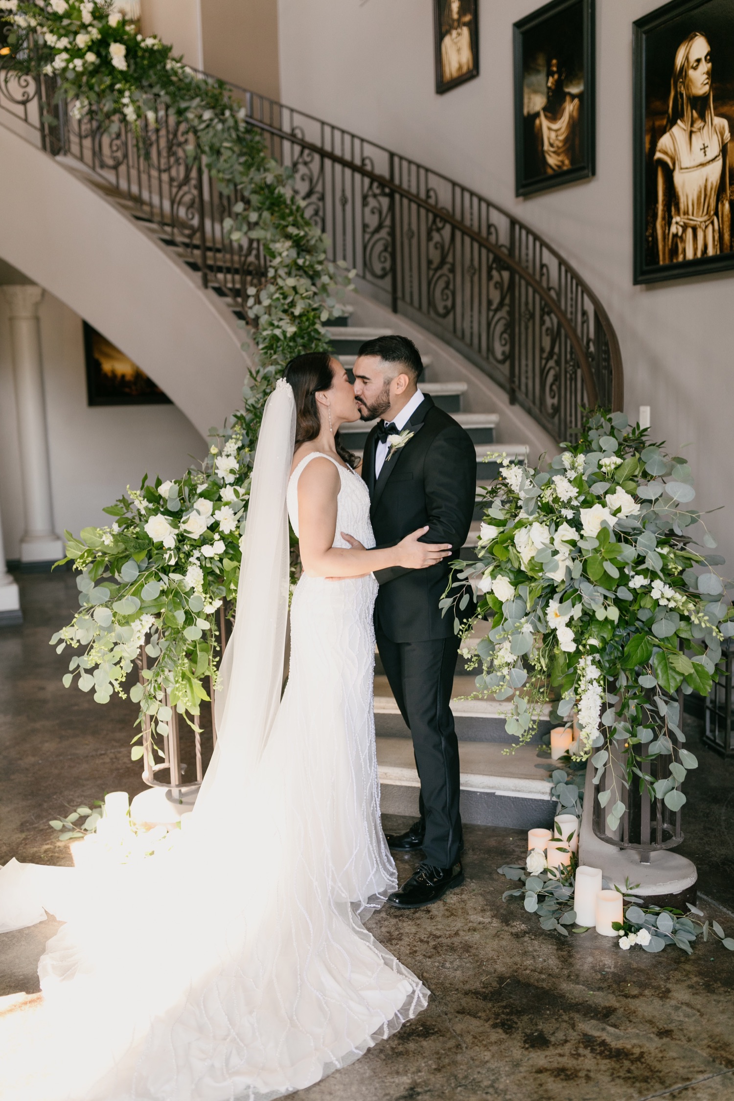 Bride and groom in front of stair case decorated with cascading flowers at Tooth and nail winery