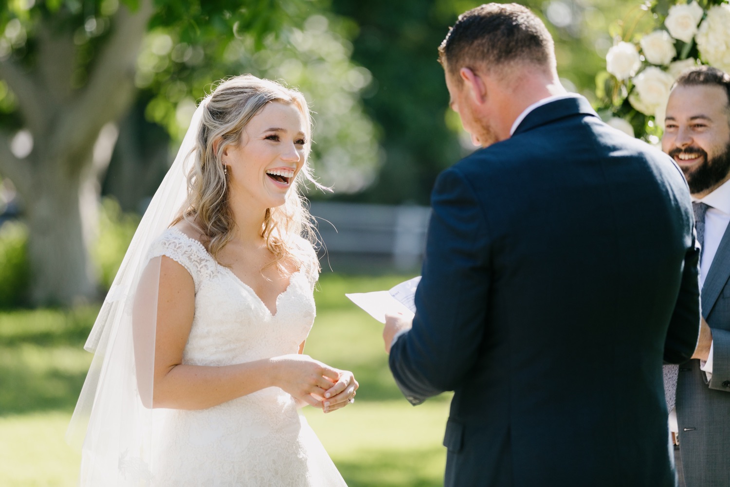 bride smiling at groom while he says his vows at walnut grove ceremony