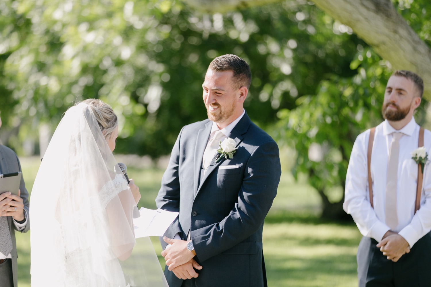 groom smiling at bride while she says her vows 
