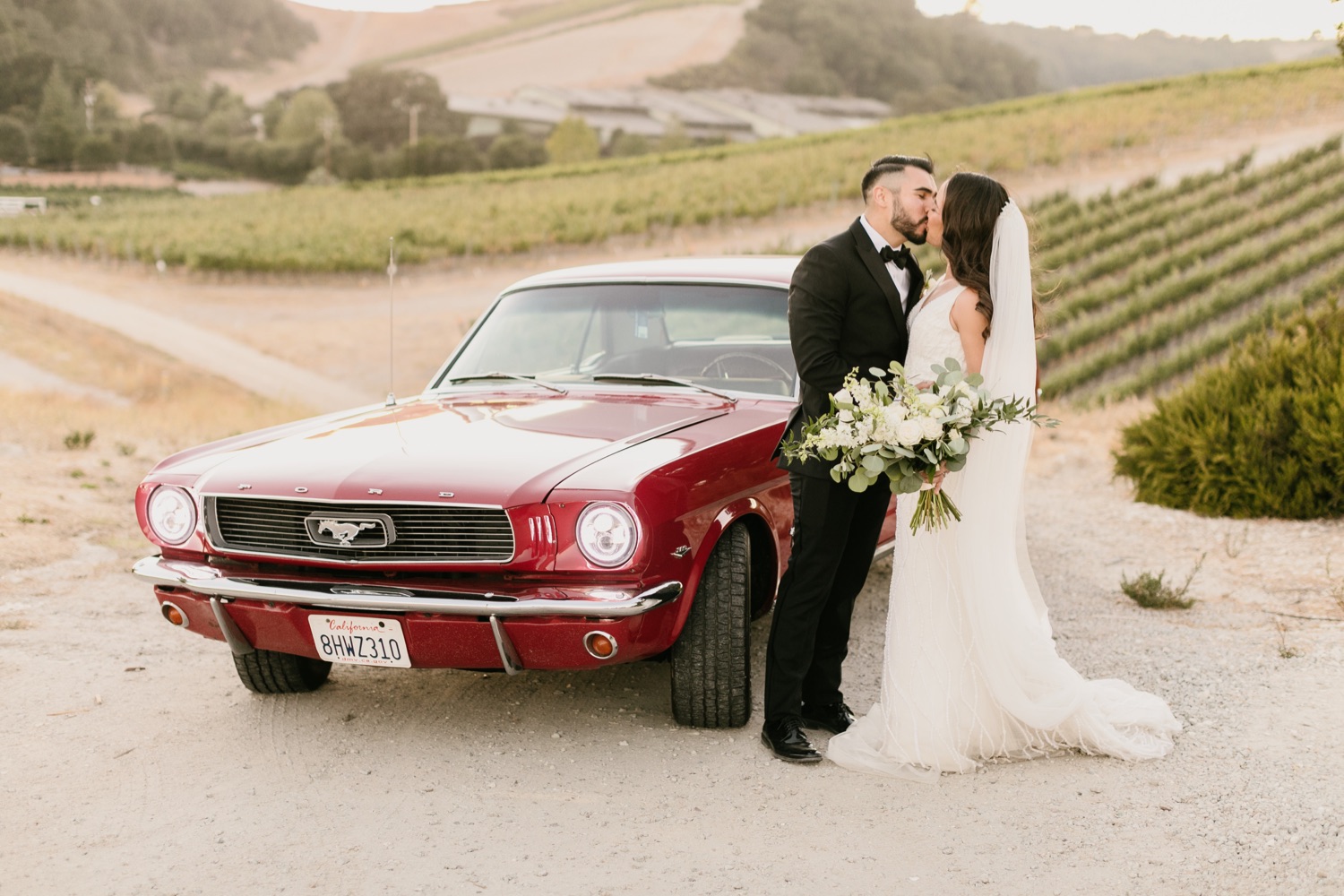 Bride and groom kissing in front of a classic car at Paso robles, california at tooth and nail winery