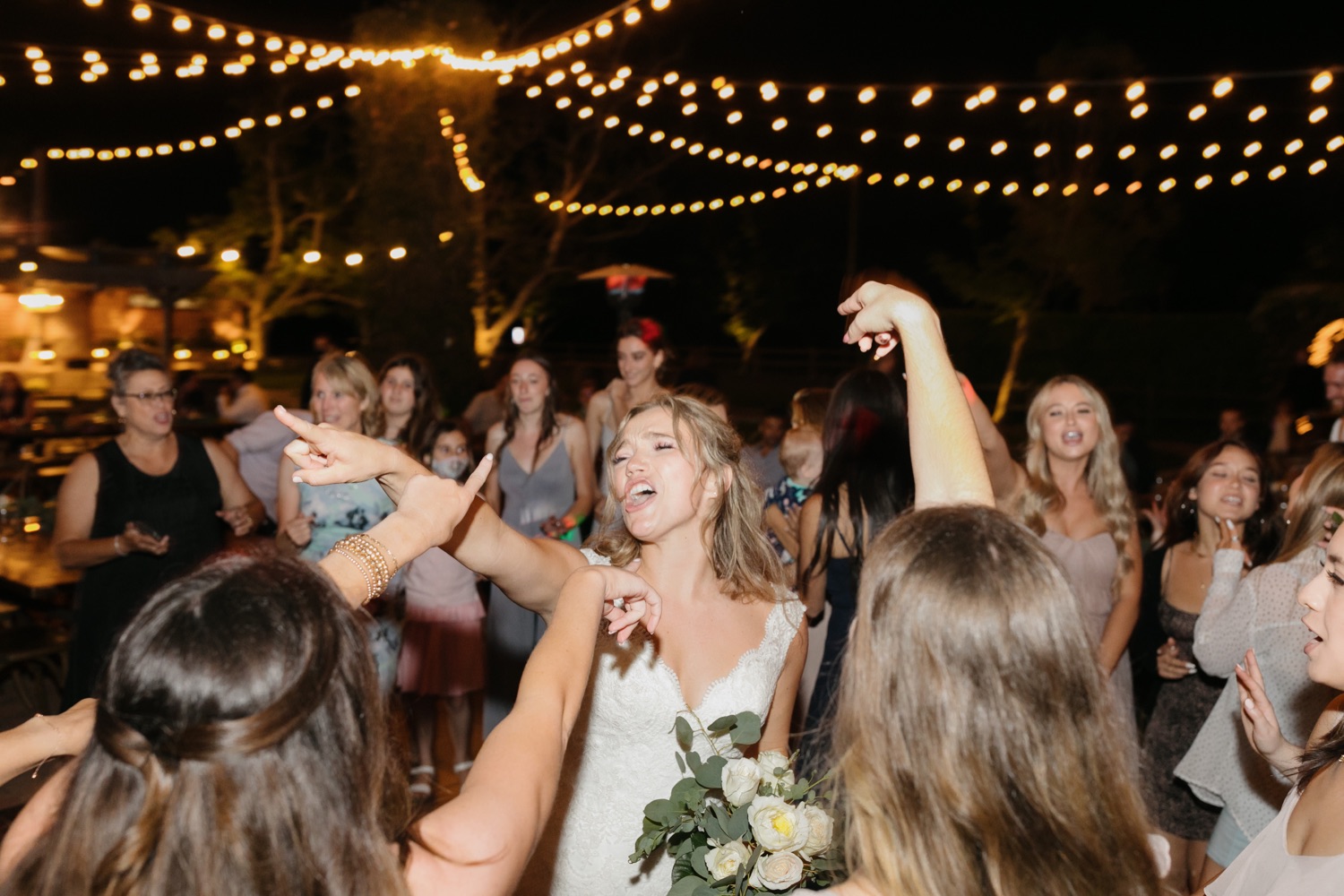 bride having fun and singing with her bridesmaids at their wedding reception
