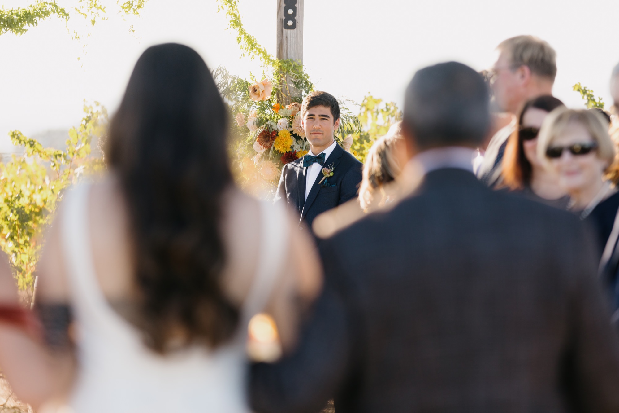 close up of Grooms first look at bride positioned from behind in between bride and her father as they are walking down the aisle at their 1800 El Pomar wedding ceremony