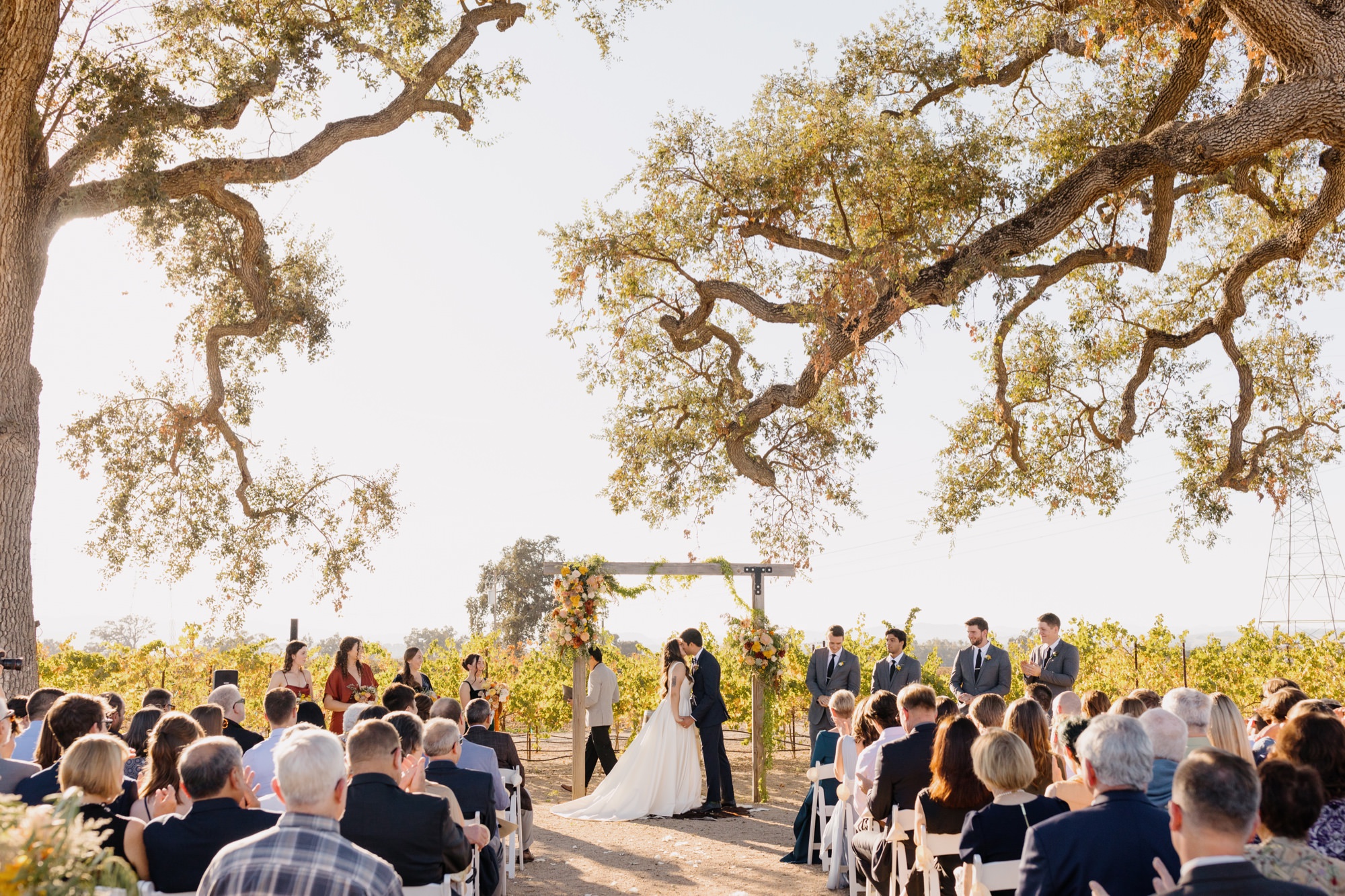 wide view of ceremony location with guests watching as the Couple's first kiss at their 1800 El pomar wedding ceremony in templeton, california