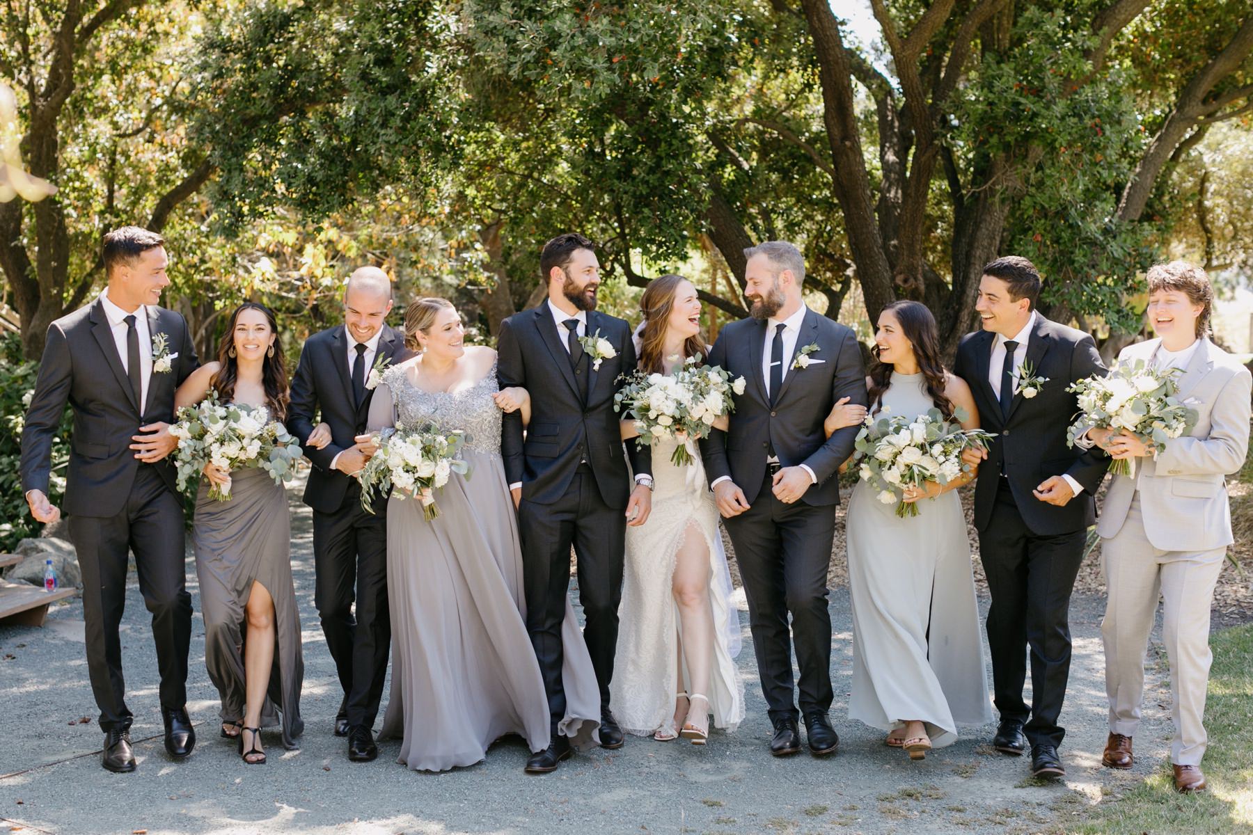 wedding party walking closely and smiling and laughing at eachother, at cal poly arboretum wedding 