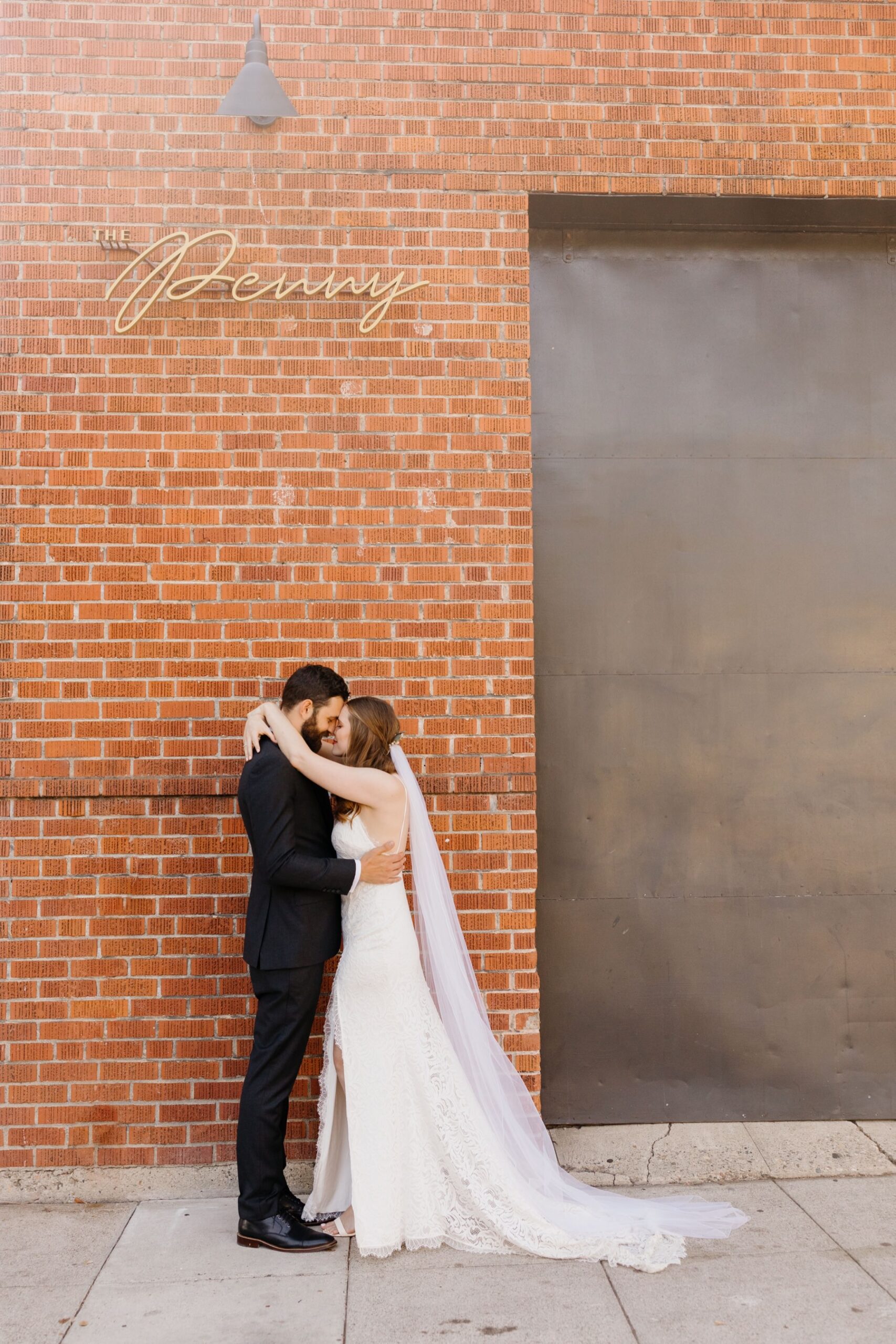 couple embracing and kissing in front of the penny wedding reception venue in san luis obispo, california