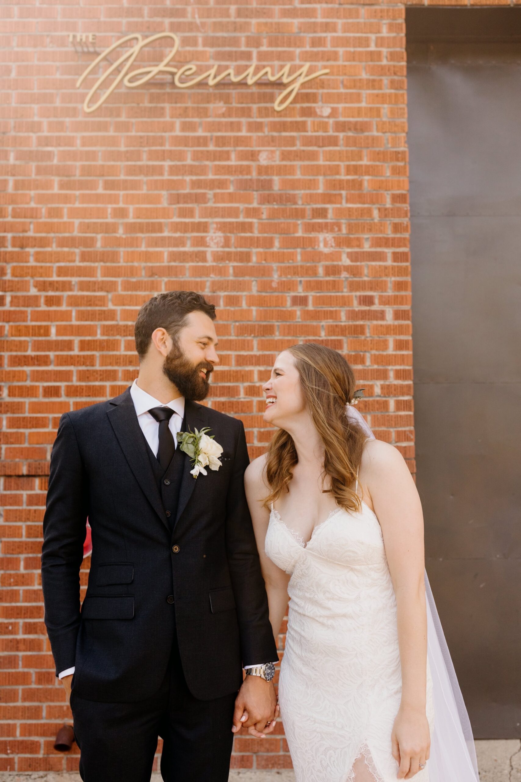 Couple laughing and smiling at eachother after their cal poly ceremony and in front of the Penny where their wedding reception is held