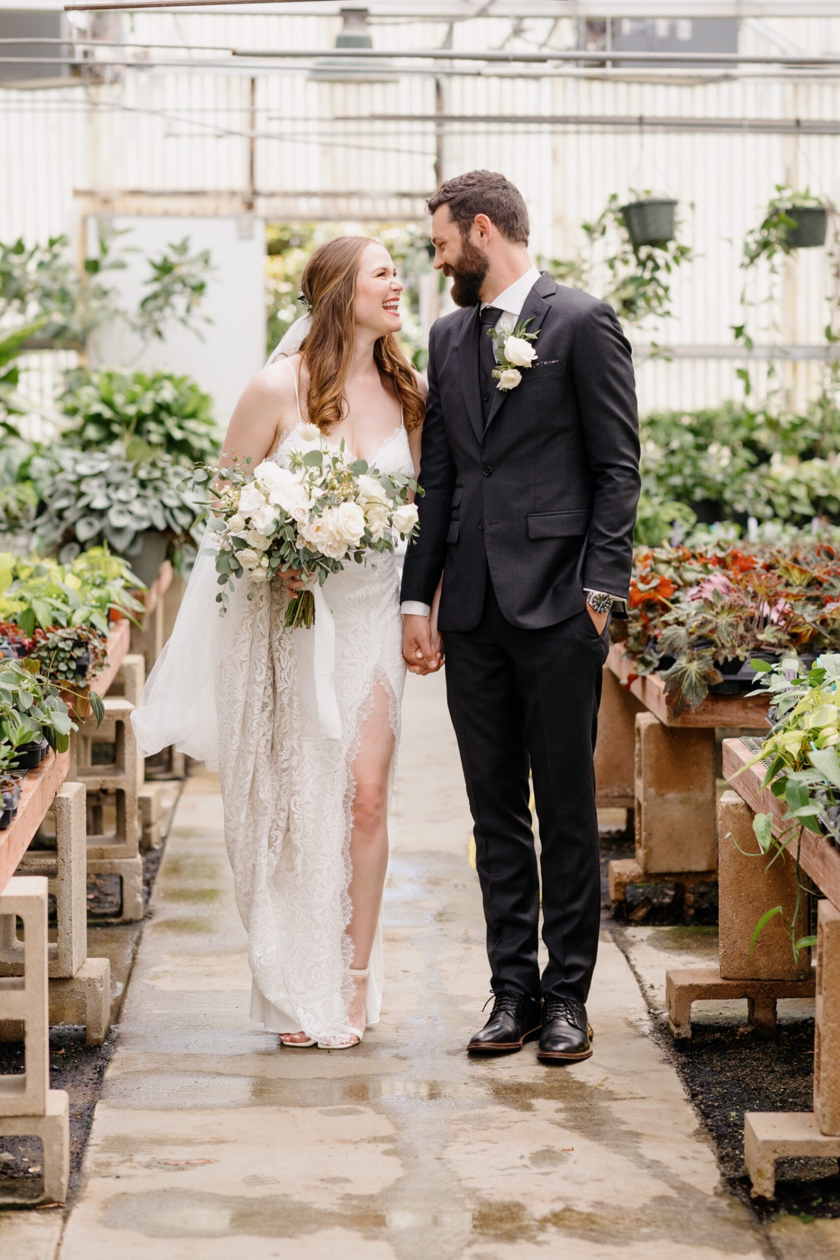 a bride and groom smiling at eachother after their first look at the green houses at the cal poly arboretum where they had their ceremony