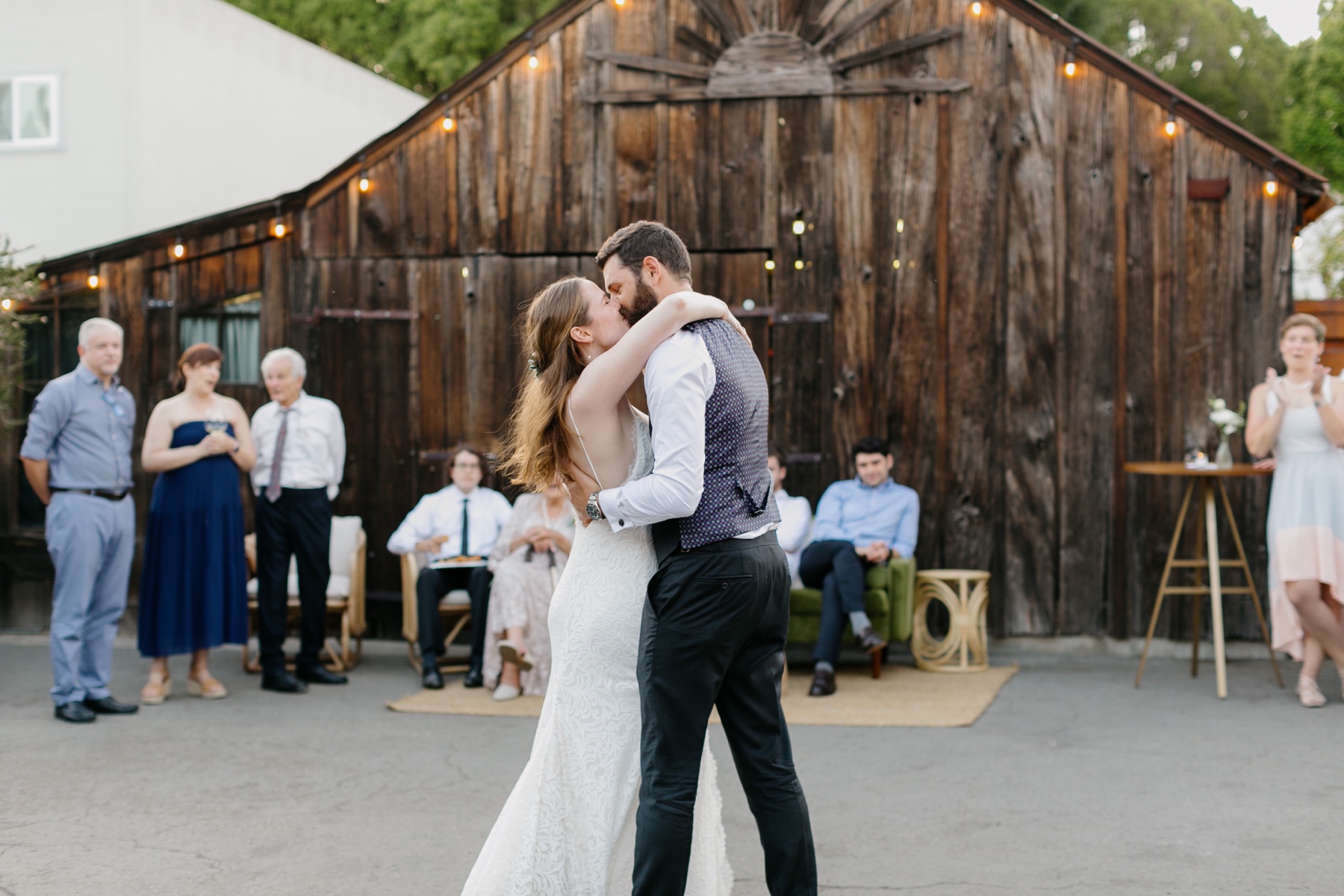 Bride and groom share a kiss during their first dance in front of a 