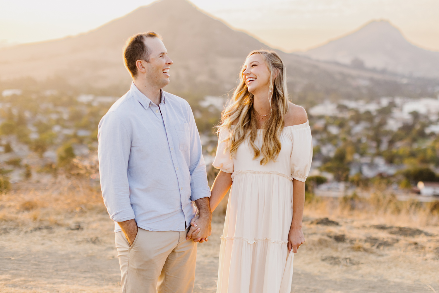 couple holding hands and laughing together at their maternity session at terrace hill in San Luis Obispo california photographed by tayler enerle