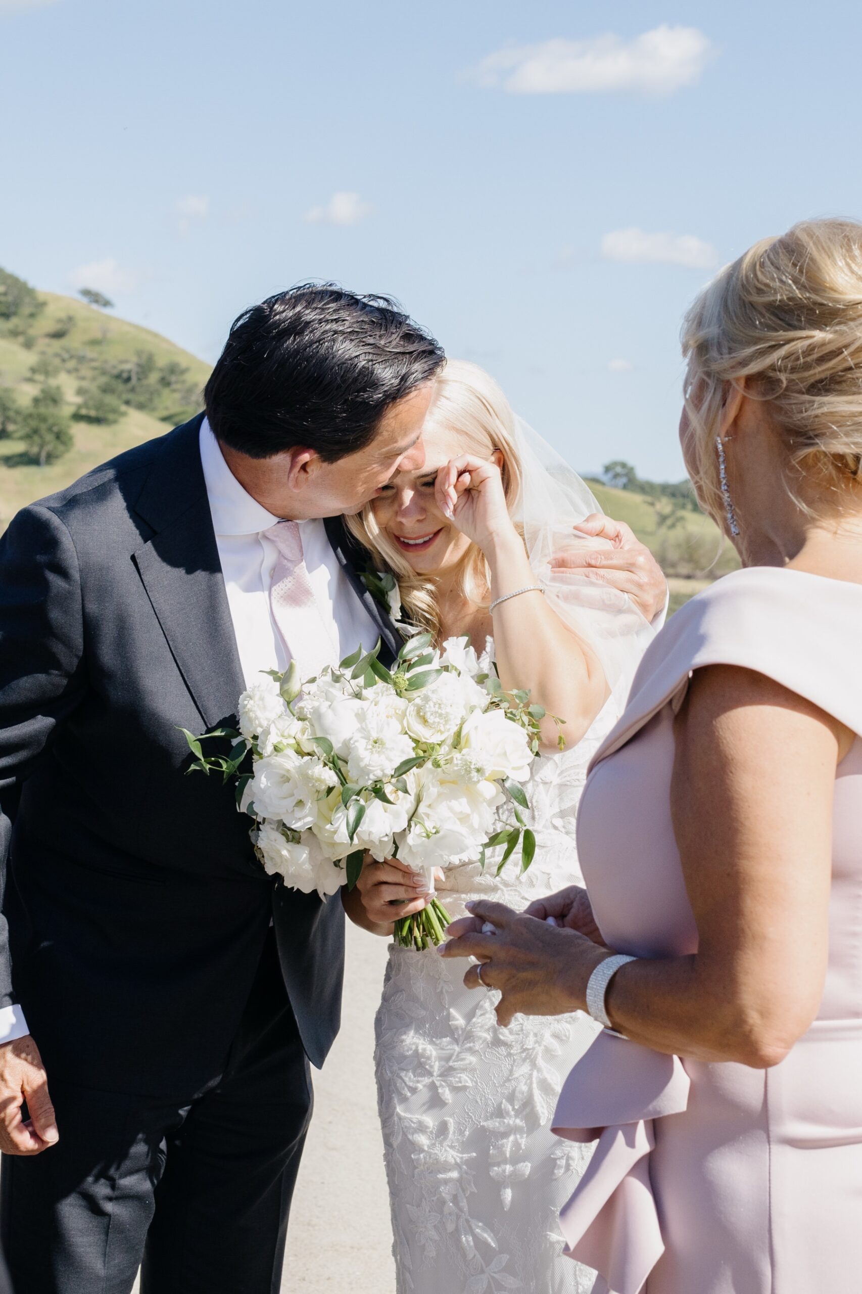 Sweet close up ohoto of a bride and her stepdad embracing her right after her ceremony while she is wiping a tear away