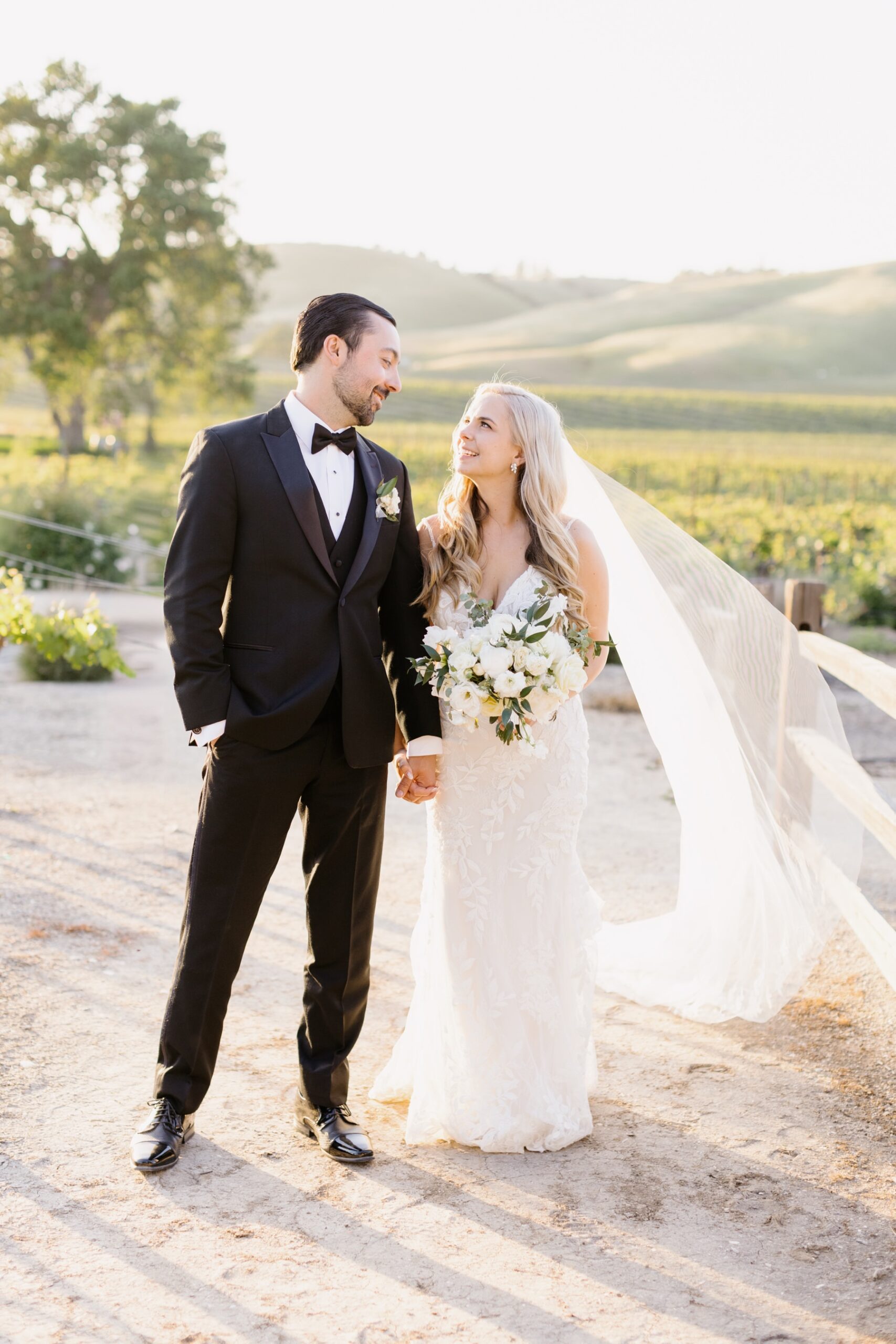 Bride and groom holding hands and looking at eachother lovingly at their sunset portrait session at Cass Winery in Paso Robles California by Tayler Enerle Photography 