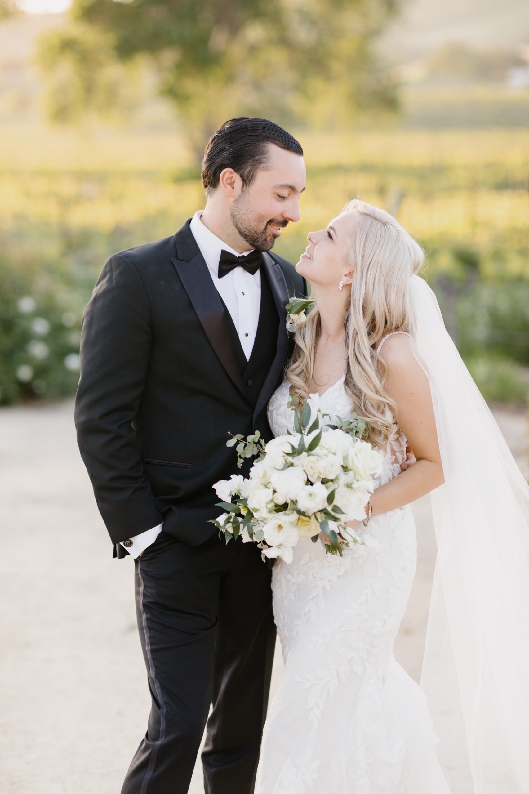 Bride and groom holding hands and looking at eachother lovingly at their sunset portrait session at Cass Winery in Paso Robles California by Tayler Enerle Photography 