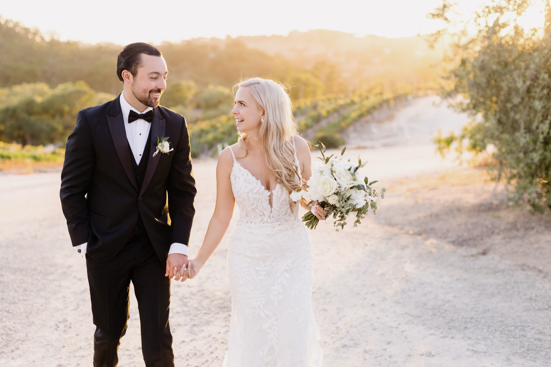 Bride and groom holding hands and looking at eachother lovingly at their sunset portrait session at Cass Winery in Paso Robles California by Tayler Enerle Photography 